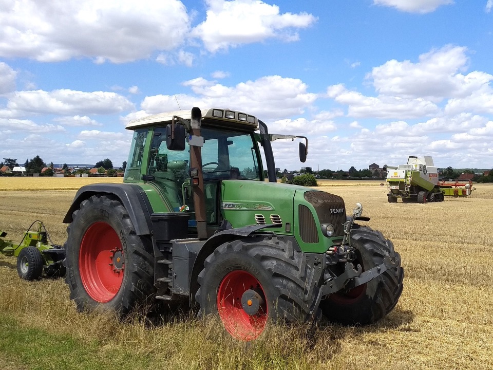 Riesiges Getreidefeld mit einem Traktor und einem Mähdrescher – Hier ist wenig Lebensraum für Vögel.